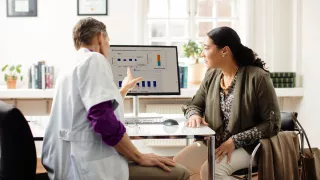 A doctor and patient sitting at a desk discussing what they are viewing on a computer screen