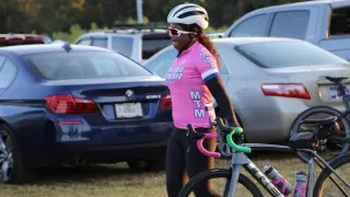 Female cyclist in pink shirt and helmet beside her bicycle