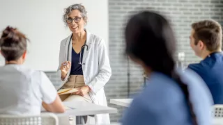 Female doctor in white coat discussing with coworkers in hospital setting