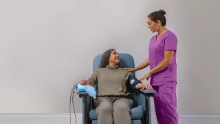 A nurse assisting a patient seated in a chair, providing care and support