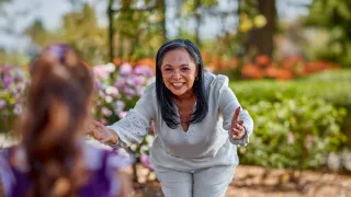 Woman holding out arms to give young girl a hug