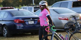 Female cyclist in pink shirt and helmet beside her bicycle