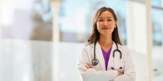 A doctor standing confidently in front of large windows