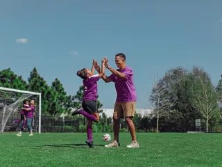 A man and a young girl playing soccer on a field, enjoying a fun and active game together