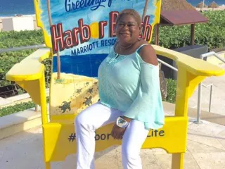 Woman sitting on beach chair with sign 'Harbor Beach' in the background