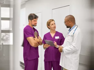 Three doctors discussing in a hospital hallway