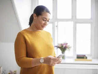 Patient standing with mobile device in their home