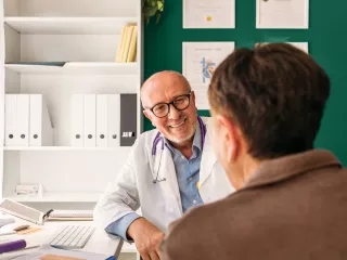 Healthcare provider consulting with a patient in front of a desktop computer