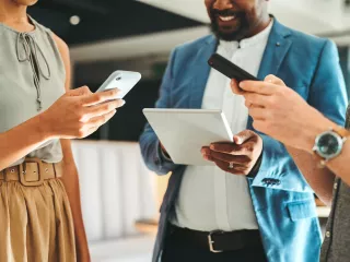 Group of professionals in office, gathered around computer screens, reading news updates
