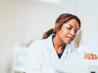 A man and woman in lab coats and safety glasses repairing a medical device