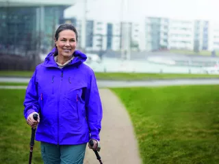 Woman walking in a green space in front of modern buildings