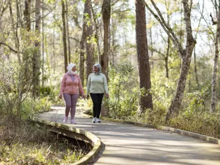 Two women walking on forest path