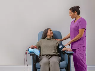 A nurse assisting a patient seated in a chair, providing care and support